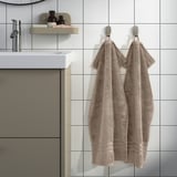 Modern bathroom with BROKGLIM towels, sink, and mirror. Organic cotton, toiletries shelf.