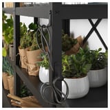 Black metal shelf with potted plants and hanging scissors, modern design.
