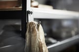 Black BROR hook holds gray towels on metal shelf, simple and sturdy.