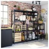 Black metal storage shelves against a brick wall. Contains various kitchen items, plants, and tools. Attached to a dark cabinet and near a window.