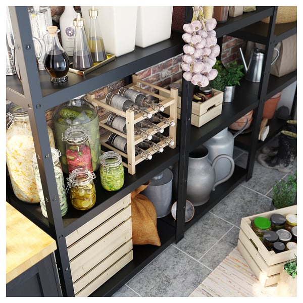 Black metal shelving unit filled with jars of preserved food and bottles, wooden crates, and kitchen tools.