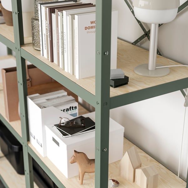 A wooden and metallic shelf unit storing books, boxes, a lamp, and wooden toys. The sturdy design supports heavy loads.