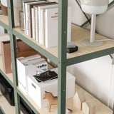 A wooden and metallic shelf unit storing books, boxes, a lamp, and wooden toys. The sturdy design supports heavy loads.