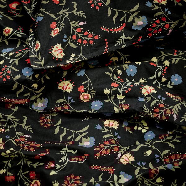 Black duvet cover with red, blue, yellow flowers, folded, intricate pattern.