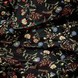 Black duvet cover with red, blue, yellow flowers, folded, intricate pattern.