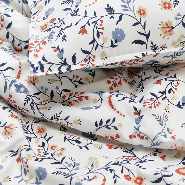 Floral duvet set, soft organic cotton, white with blue, orange, and beige flowers, folded neatly.