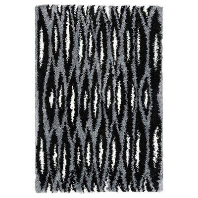 Black and white striped rectangular rug with a shaggy texture. Part of the nytillverkad collection, it a modern design with diagonal patterns.