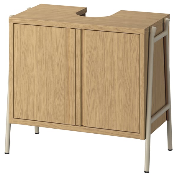 An oak BYASJÖN bathroom storage cabinet with two doors, a soft-close feature, and metal legs.