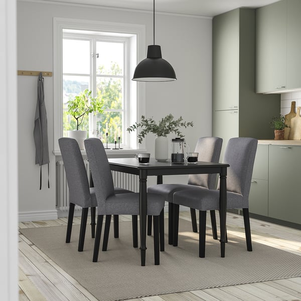 Modern dining set with black table, grey chairs. Light fills bright room.