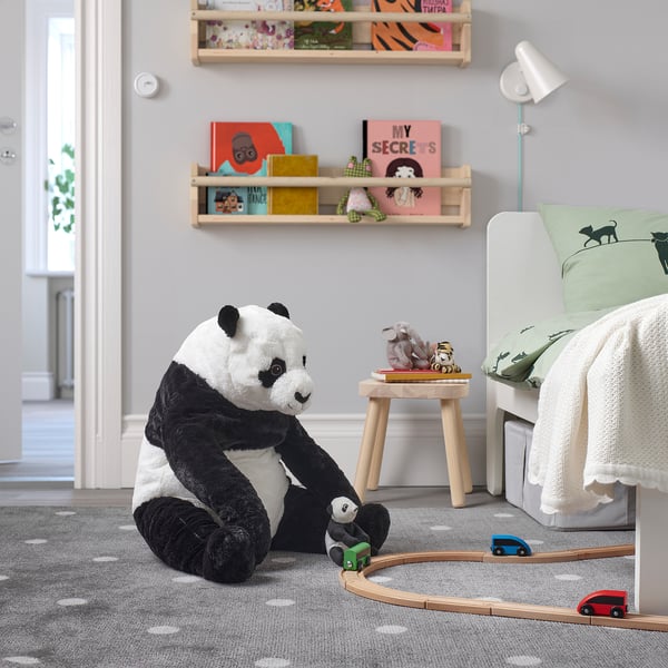 Panda toy on rug with trains, bed, stool, and bookshelf.