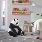 Panda toy on rug with trains, bed, stool, and bookshelf.