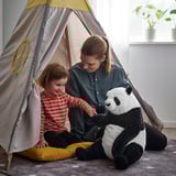 A woman and a toddler play inside a beige and yellow tent with a plush panda toy, promoting bonding and comfort.