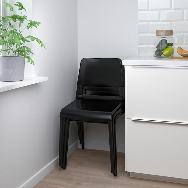 A sleek black DOCKSTA chair tucked neatly next to kitchen cabinets, showcasing its space-saving design and modern appeal.
