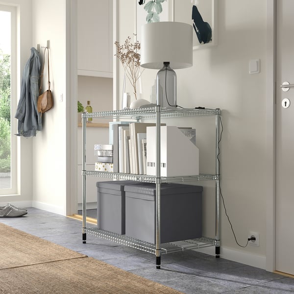 Modern entryway with grey DRÖNA storage boxes on metal shelf under cabinets. Grey lid on middle box. Space-saving design.