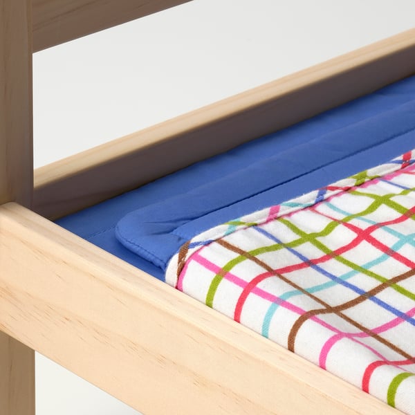 Wooden doll bed with blue mattress and multi-colored patterned blanket, showcasing high-quality craftsmanship and inviting texture.
