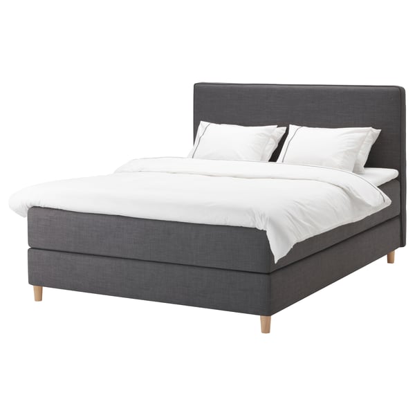 DUNVIK bed: dark grey, upholstered with wood legs, rectangular shape, soft headboard, white linens.