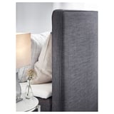 Modern bed with gray upholstered headboard and white pillows, set against a light wall. Simple, elegant design.