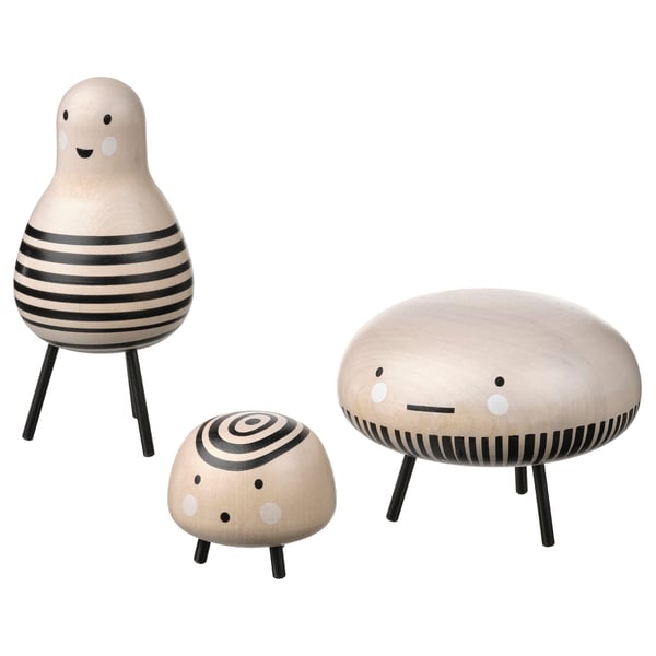 Three wooden figurines: two round, smiling, one with stripes; one smaller with circles. Black legs, white faces.