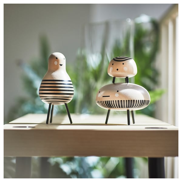 Two DVÄRGTALL wooden figurines on a shelf, one white with black stripes and the other beige with black stripes.