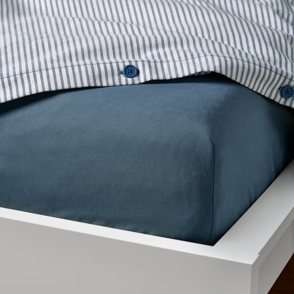 Bed fitted sheet with blue stripe pillow cover, dark blue fabric, white bed frame.