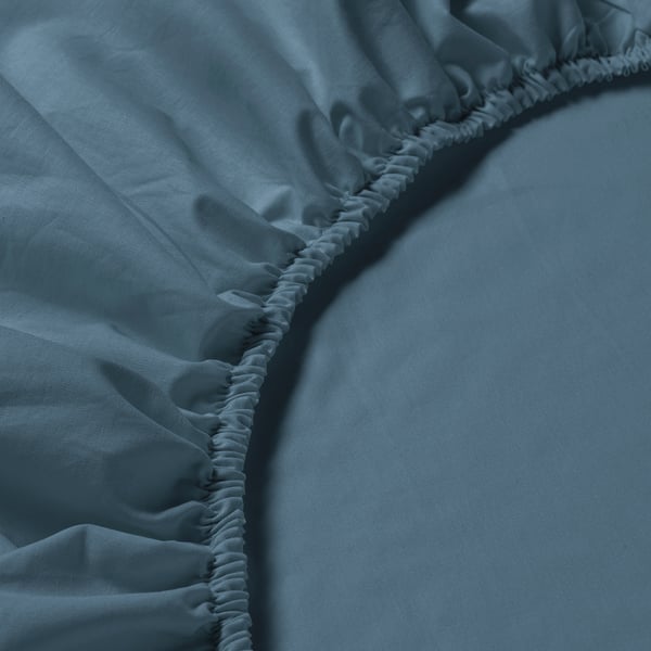 Close-up view of blue DVALA bed sheets elastic hem, showing high-quality stitching and fabric texture.