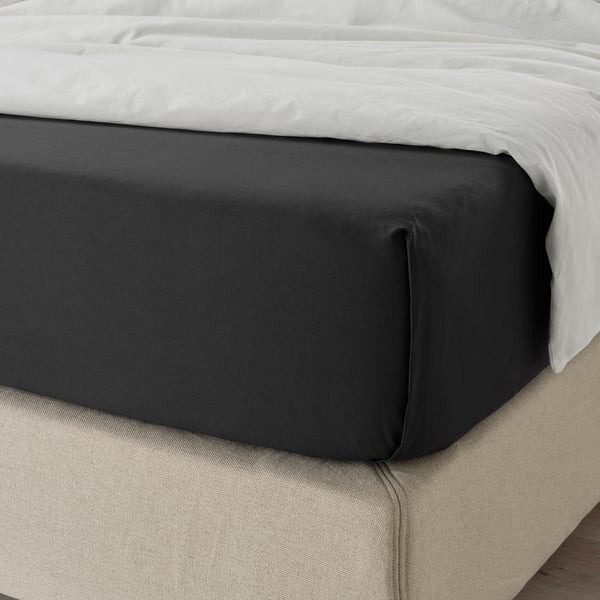 Black cotton bed linen, neatly arranged on a white bed. Shows soft, breathable fabric for comfort and sustainability.