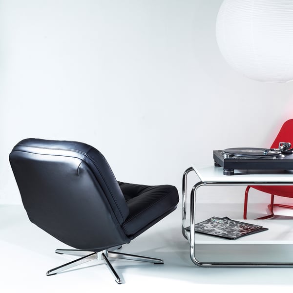 Modern black leather DYVLINGE chair, chrome base, by IKEA. Its small, compact, next to a white table with a red record player.