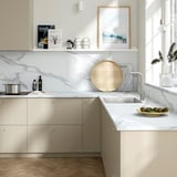 Modern kitchen with white marble countertop, stainless steel sink, and light wood accents. Smooth, rectangular drawers and minimalist design.