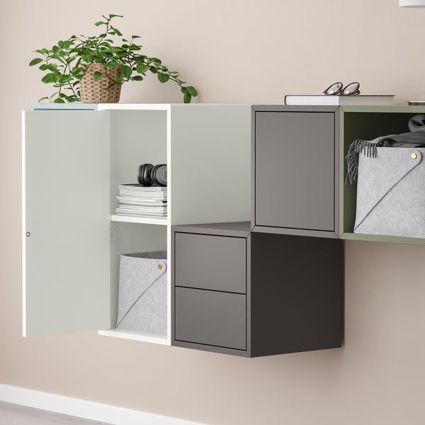 Wall-mounted storage units with open and closed cabinets. Top shelf holds a plant, books, and accessories.