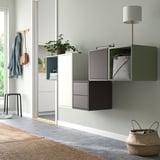 Modern room with wall-mounted EKET cabinets in green & grey, combining open & closed storage, asymmetric setup.