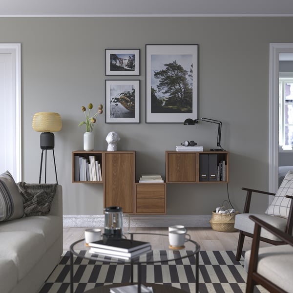 Modern living room with grey walls, EKET storage, grey sofa, striped rug, coffee table with mugs, and framed photos.
