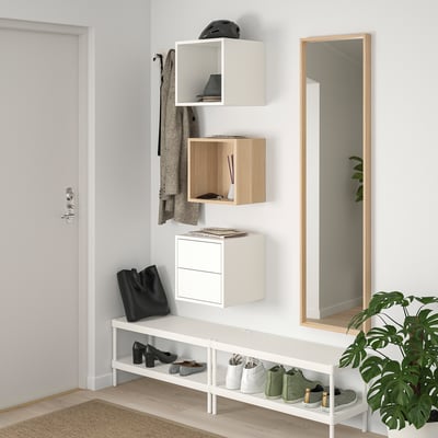 Two modern storage cubes: one white, one light wood. Square shape, minimalist design, open and closed compartments.