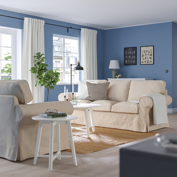Cozy blue living room with beige EKTORP sofa, white side table, and tall plant.