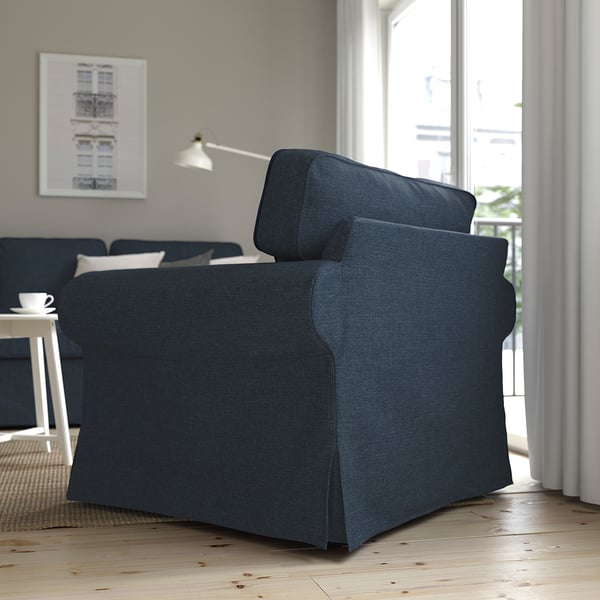 Dark grey EKTORP armchair by window in bright living room, comfy & practical with washable cover.