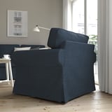 Dark grey EKTORP armchair by window in bright living room, comfy & practical with washable cover.