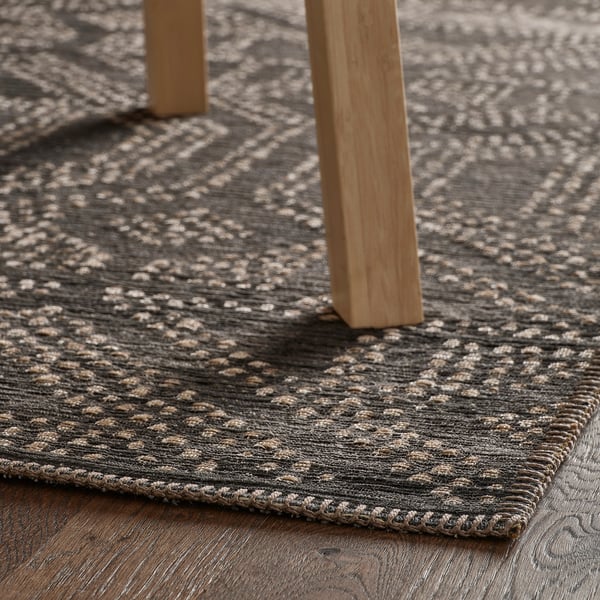 Rug under table legs. Lattice design in grey and beige. Wooden table.