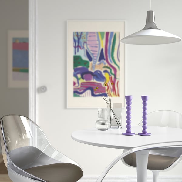 Modern dining area with white table, clear chairs, purple candlesticks, flowers, abstract art, and large pendant lamp.