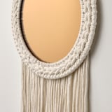 Handcrafted wall mirror with braided, beige macrame fringe. Recycled polyester. Mirrors light beautifully.