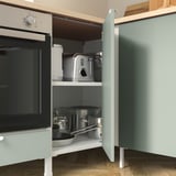 This image shows a kitchen cabinet with an oven inside. The cabinet has shelves holding pots and pans. The drawer is labeled ENHET.