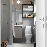 Small, modern bathroom with grey ENHET vanity, mirror, toilet, and open shelves. White accessories on counter.