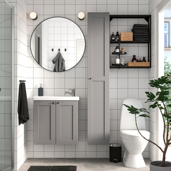 Modern bathroom with grey & white theme. Large round mirror, grey cabinet, wall shelves. Clean, minimalist look.