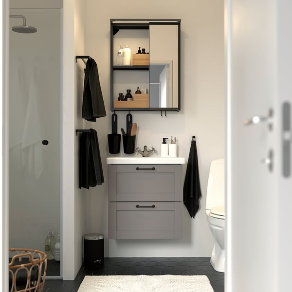 Modern bathroom with grey ENHET vanity, mirror cabinet, black accents, clean lines, and sleek design; vanity is compact yet spacious.