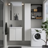 Modern bathroom with white floating cabinet, sink, mirror, and storage. Grey walls and black accents.