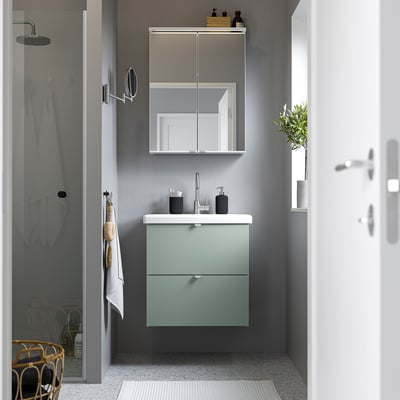 Modern bathroom with ENHET light green cabinet & mirror cabinet, stainless faucet, and glass shower.