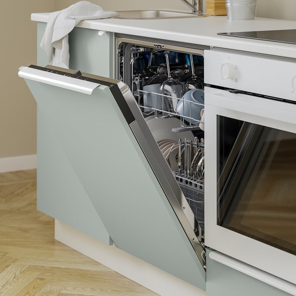 Open dishwasher in kitchen with clean dishes, light blue cabinet.