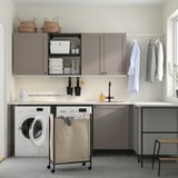Modern laundry area with ENHET cabinets. Grey cabinets, sink, washing machine, hanging rail, and storage solutions.