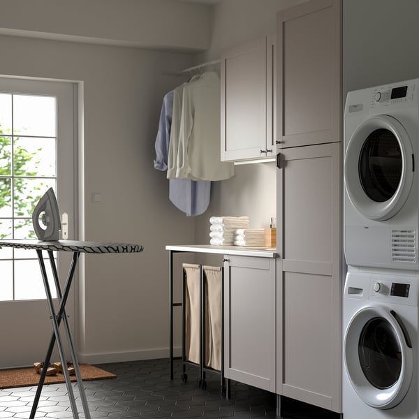 Description: modern laundry room with grey ENHET cabinets and appliances. Ironing board, clothes rail, and stacked washers.