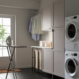 Description: modern laundry room with grey ENHET cabinets and appliances. Ironing board, clothes rail, and stacked washers.