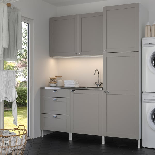 Modern grey laundry unit with sink, cabinets, and washer next to window.
