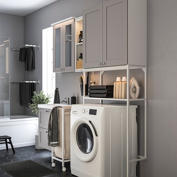 Modern grey laundry-bath combo; white washer, open shelves, glass doors, mirror.